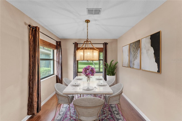 dining area with baseboards, visible vents, and wood finished floors