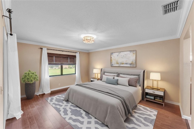 bedroom featuring crown molding, wood finished floors, and visible vents