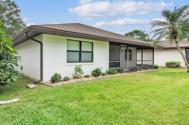 single story home featuring a sunroom, a shingled roof, stucco siding, and a front yard