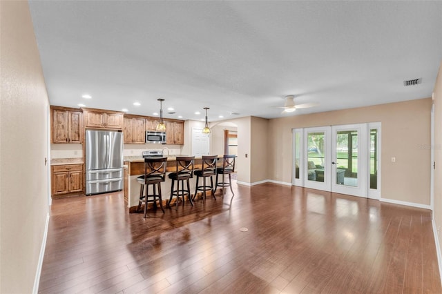 kitchen with ceiling fan, arched walkways, stainless steel appliances, a kitchen bar, and visible vents