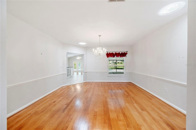 unfurnished dining area featuring a chandelier, light wood-style floors, and baseboards
