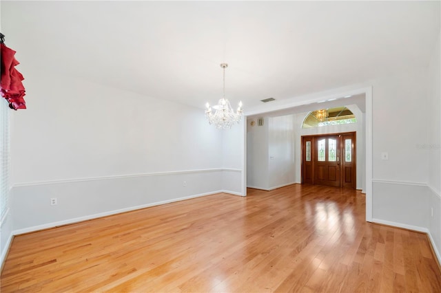 unfurnished dining area with a chandelier, light wood finished floors, and baseboards