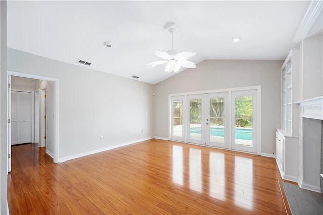 unfurnished living room with light wood finished floors, french doors, lofted ceiling, a fireplace with flush hearth, and ceiling fan