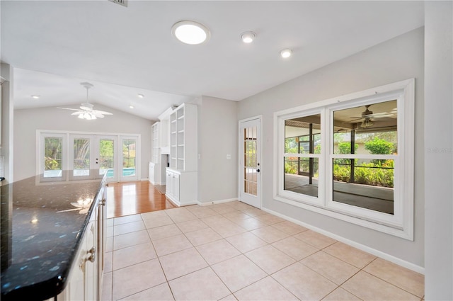 kitchen featuring a ceiling fan, french doors, lofted ceiling, light tile patterned floors, and dark stone countertops