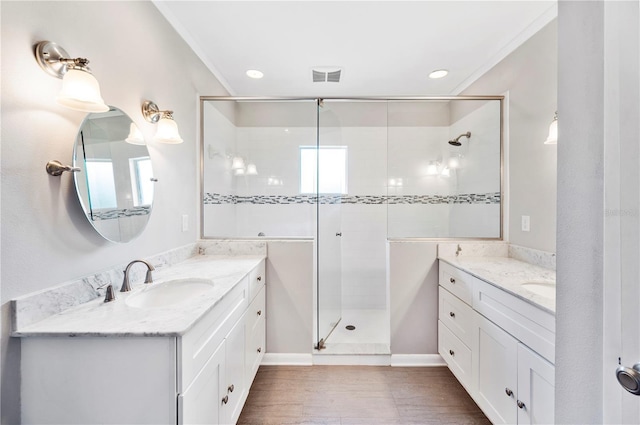 bathroom featuring a stall shower, two vanities, ornamental molding, wood finished floors, and recessed lighting