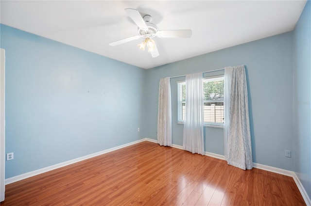 spare room featuring baseboards, wood finished floors, and a ceiling fan
