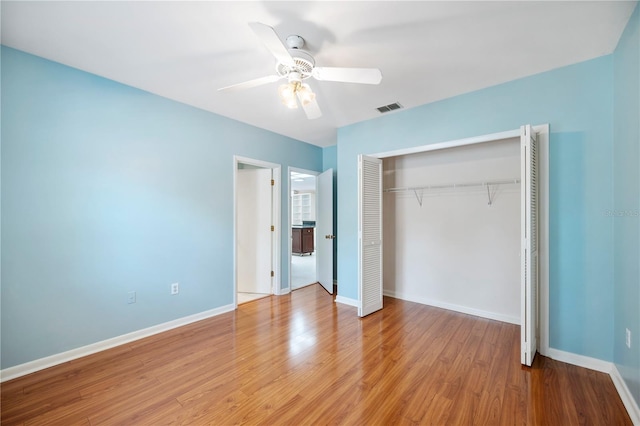 unfurnished bedroom featuring a closet, wood finished floors, baseboards, and a ceiling fan