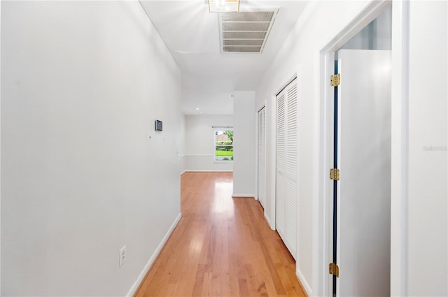 hall featuring light wood-style flooring and baseboards