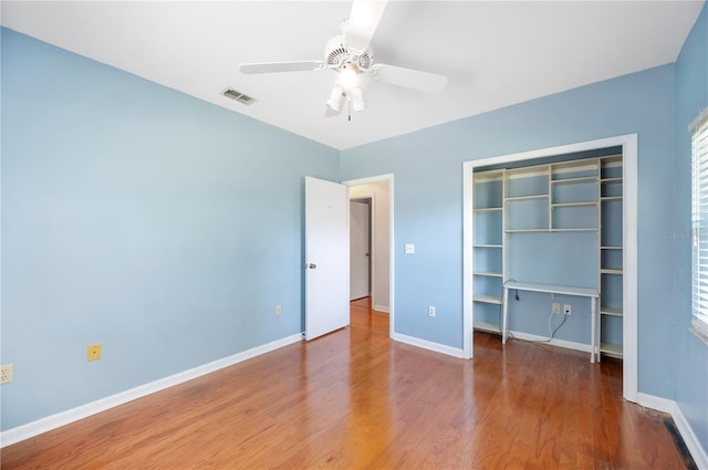 unfurnished bedroom featuring baseboards, a closet, wood finished floors, and a ceiling fan