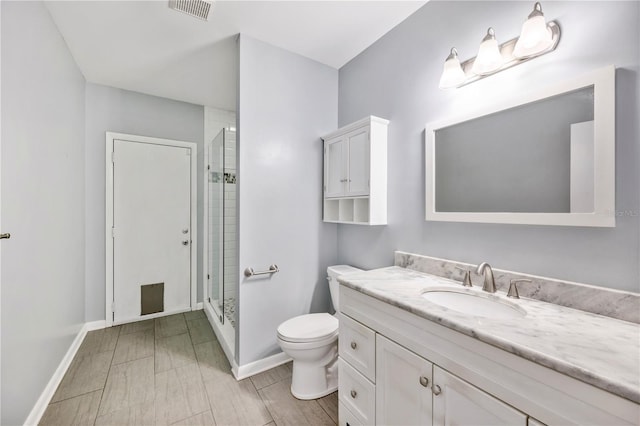 bathroom featuring a shower with shower door, toilet, baseboards, and vanity