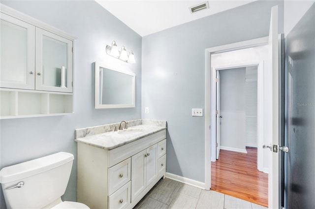 bathroom with vanity, toilet, and baseboards