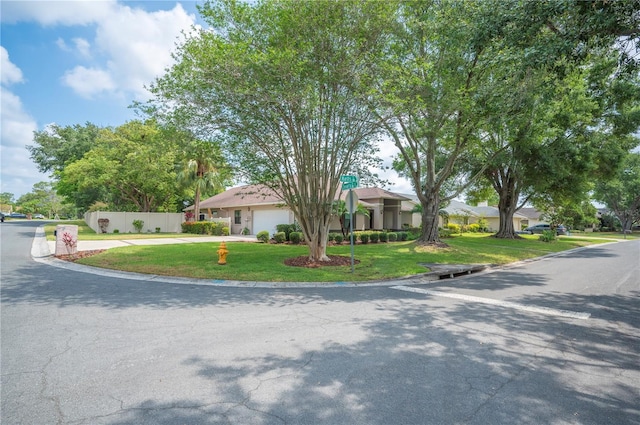view of front facade featuring a front yard, an attached garage, and driveway