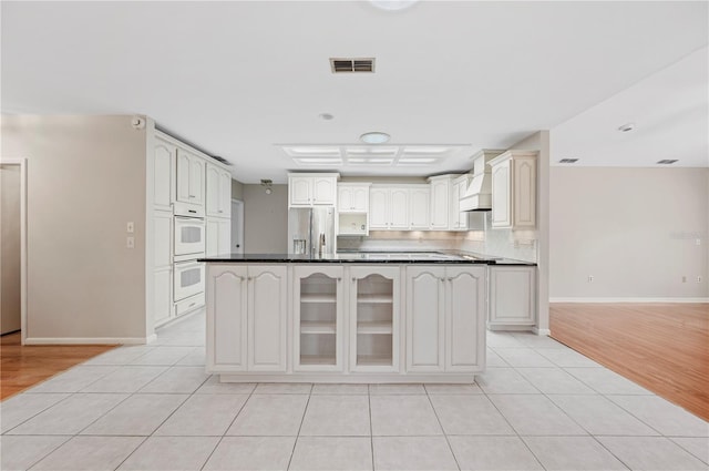 1104 Kells Ct, Lakeland, FL 33813 - kitchen featuring stainless steel fridge with ice dispenser, double oven, dark countertops, and light tile patterned flooring