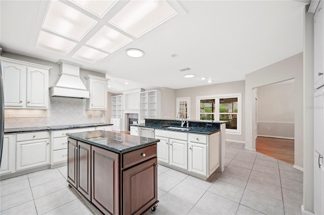 1104 Kells Ct, Lakeland, FL 33813 - kitchen with a center island, a sink, custom range hood, backsplash, and white cabinetry