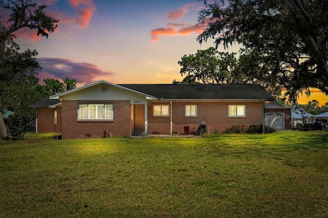 view of front of property with brick siding, a yard, and a garage
