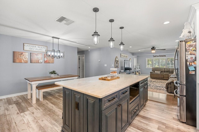 kitchen with light wood finished floors, visible vents, a ceiling fan, freestanding refrigerator, and open floor plan