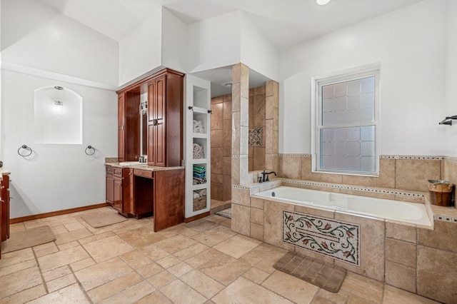 full bath featuring a bath, walk in shower, vanity, and stone tile floors