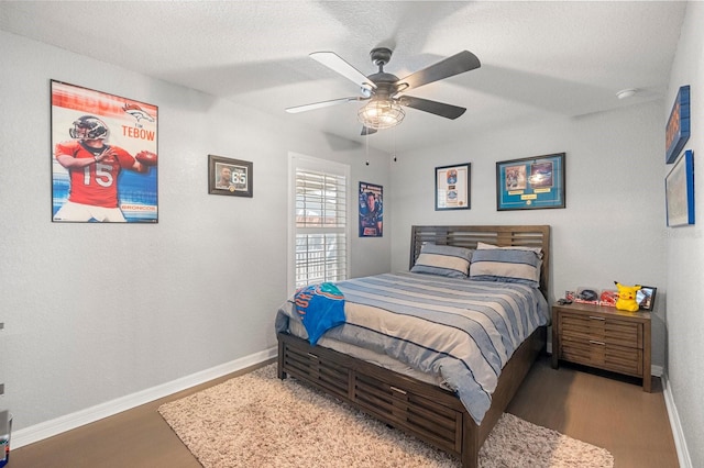 bedroom with wood finished floors, baseboards, a textured ceiling, and a ceiling fan