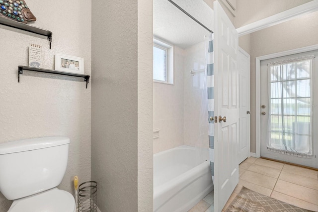 full bath featuring toilet, a textured wall, shower / tub combo with curtain, and tile patterned floors