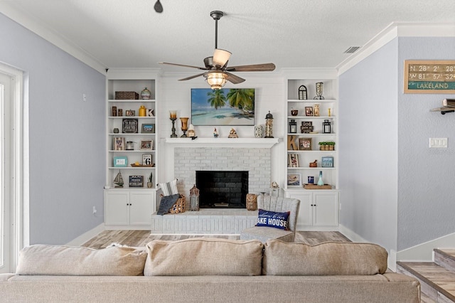 living area featuring a textured ceiling, wood finished floors, ceiling fan, a fireplace, and visible vents
