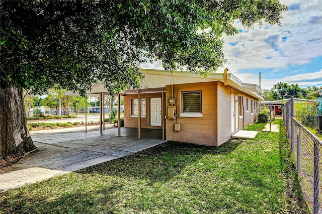 exterior space with fence, a lawn, an attached carport, and concrete block siding