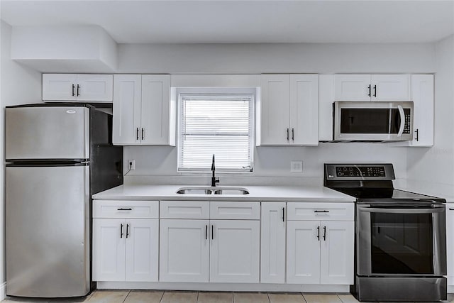 kitchen with appliances with stainless steel finishes, a sink, white cabinetry, and light countertops