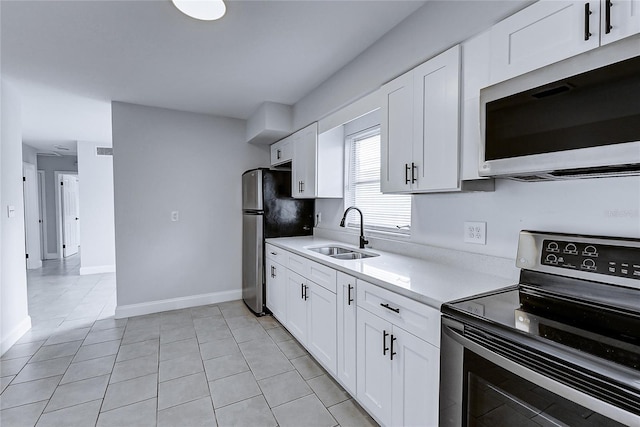 kitchen with stainless steel appliances, a sink, white cabinetry, light countertops, and light tile patterned floors