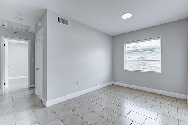 unfurnished room with attic access, baseboards, light tile patterned flooring, and visible vents