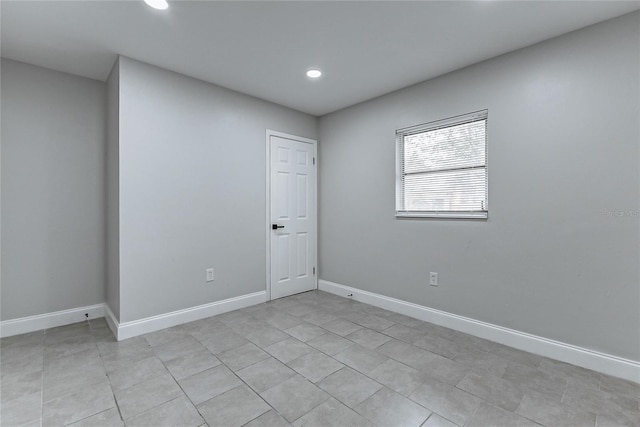 empty room with light tile patterned floors, baseboards, and recessed lighting