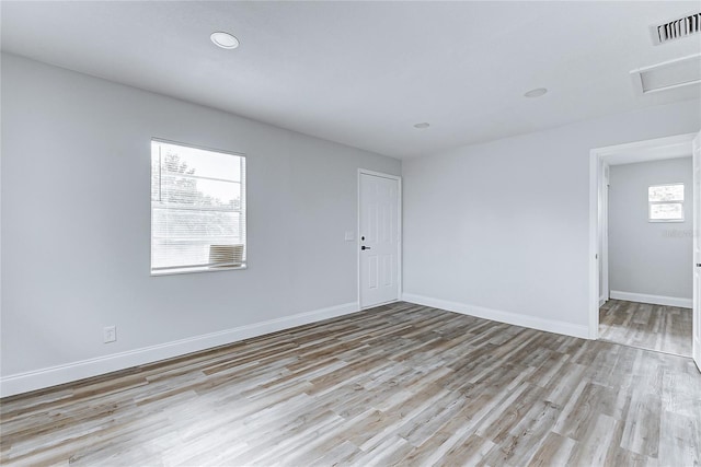 spare room featuring light wood finished floors, attic access, baseboards, visible vents, and recessed lighting