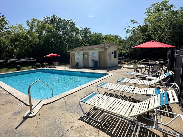 community pool featuring a patio area, an outdoor structure, and fence