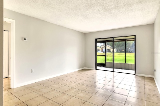 spare room with baseboards, light tile patterned flooring, and a textured ceiling