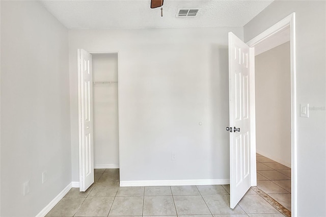 unfurnished bedroom featuring a ceiling fan, a closet, light tile patterned floors, baseboards, and visible vents