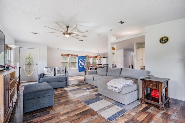 living area featuring visible vents, a ceiling fan, a textured ceiling, and wood finished floors