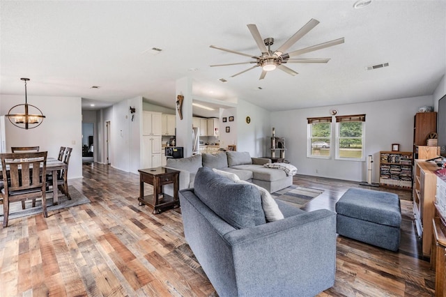 living area with visible vents, ceiling fan with notable chandelier, vaulted ceiling, and light wood-type flooring