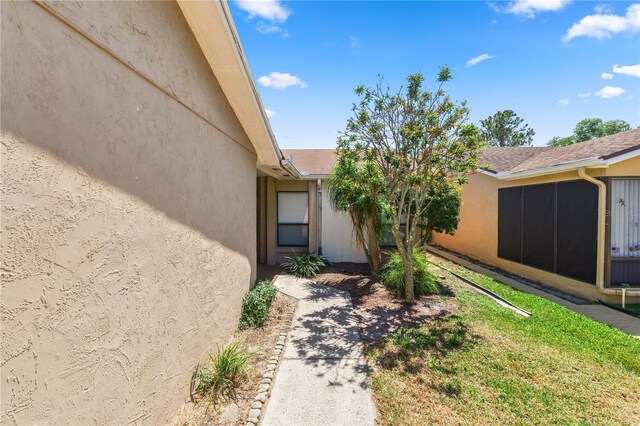 property entrance featuring a yard and stucco siding