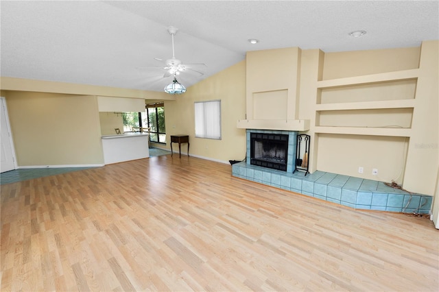 unfurnished living room with baseboards, a tile fireplace, wood finished floors, and a ceiling fan