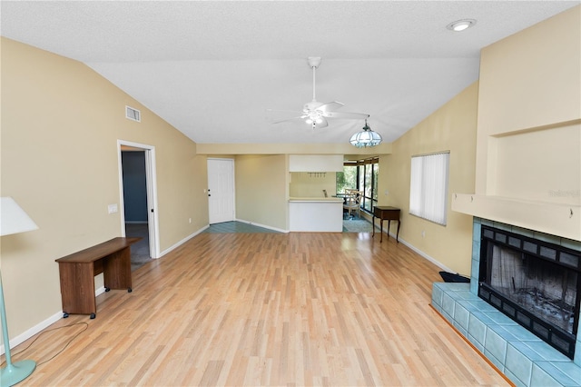 unfurnished living room featuring a ceiling fan, visible vents, a tile fireplace, and light wood-style flooring