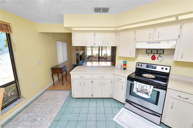 kitchen featuring under cabinet range hood, light countertops, visible vents, stainless steel electric range, and a peninsula