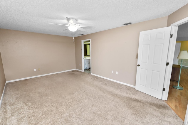carpeted spare room featuring ceiling fan, baseboards, a textured ceiling, and visible vents