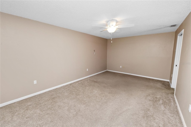 carpeted empty room featuring ceiling fan, baseboards, a textured ceiling, and visible vents