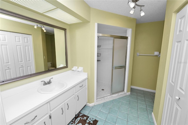 bathroom with baseboards, toilet, vanity, and a stall shower