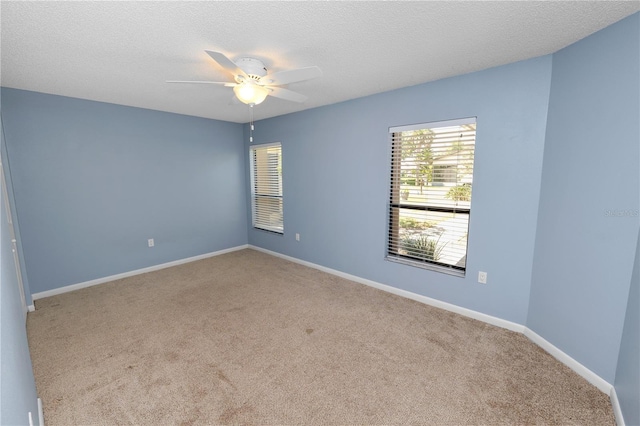 carpeted empty room featuring ceiling fan, baseboards, and a textured ceiling