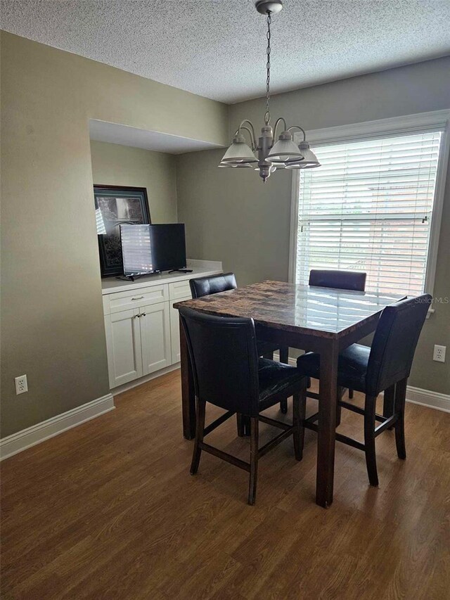 dining room featuring a chandelier, a textured ceiling, dark wood-type flooring, and baseboards