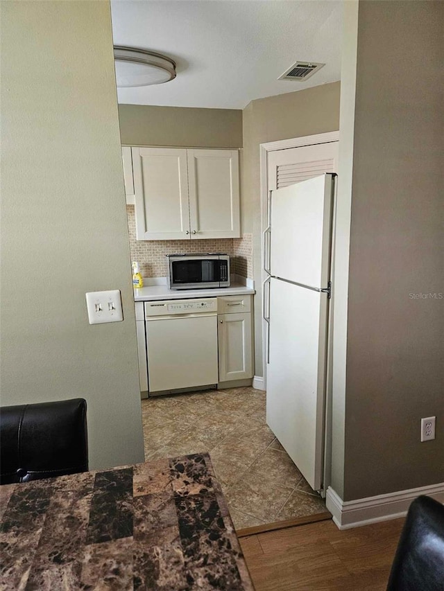 kitchen with white appliances, white cabinets, decorative backsplash, and baseboards