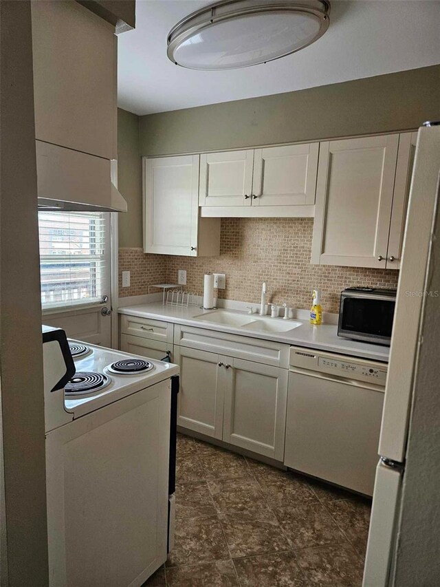 kitchen featuring white appliances, a sink, white cabinetry, light countertops, and backsplash