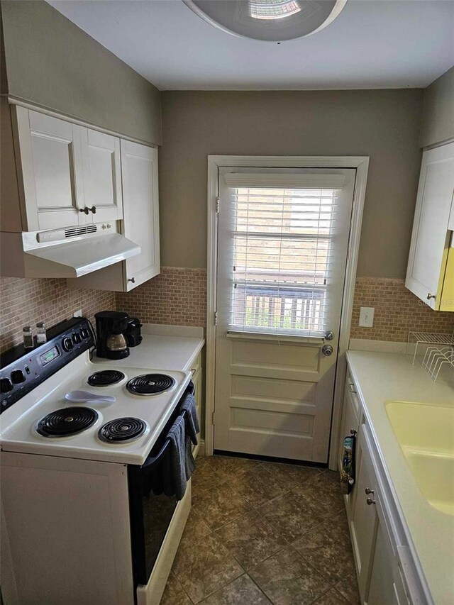 kitchen featuring electric range oven, under cabinet range hood, a sink, white cabinets, and light countertops