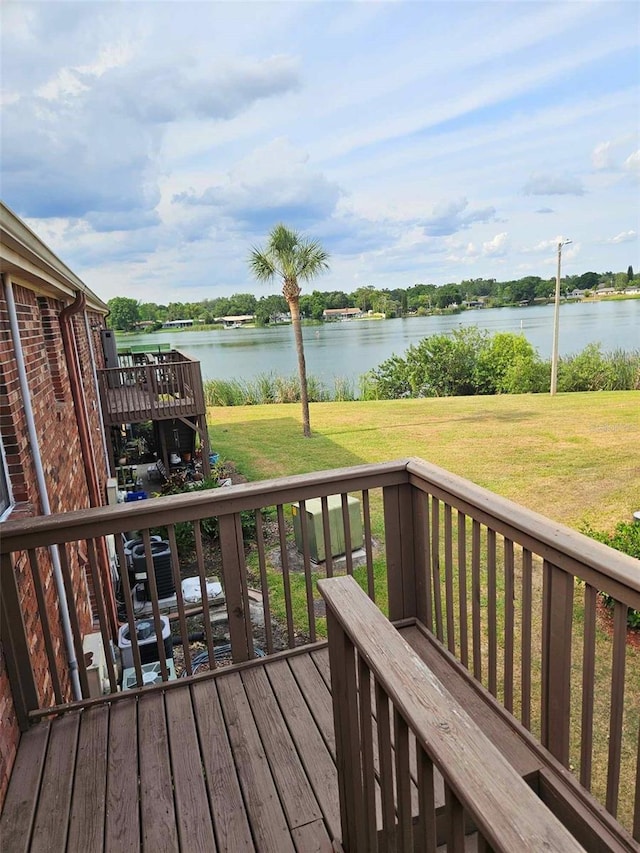 wooden terrace featuring a water view and a lawn