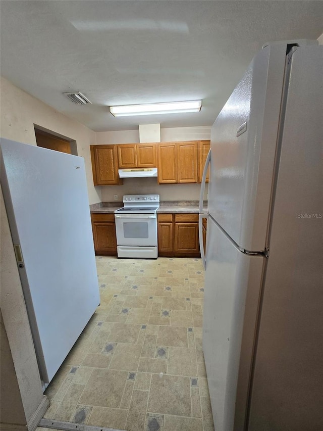 911 White Ln NE, Steinhatchee, FL 32359 - kitchen featuring white appliances, brown cabinetry, under cabinet range hood, light countertops, and visible vents