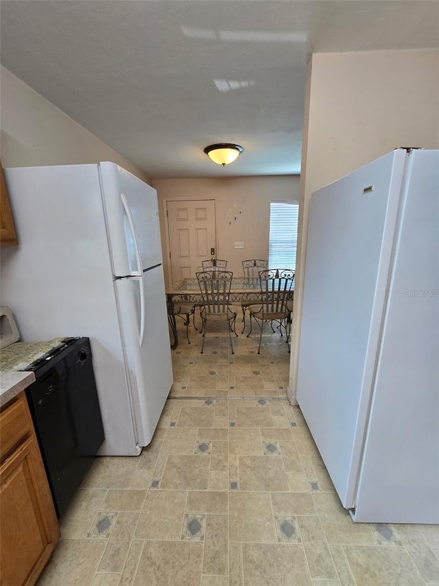 911 White Ln NE, Steinhatchee, FL 32359 - kitchen featuring brown cabinets, dishwasher, and freestanding refrigerator